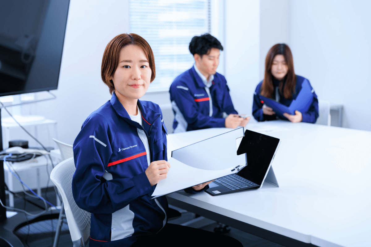 スーツ姿で笑顔の男女社員がオフィスに立つ