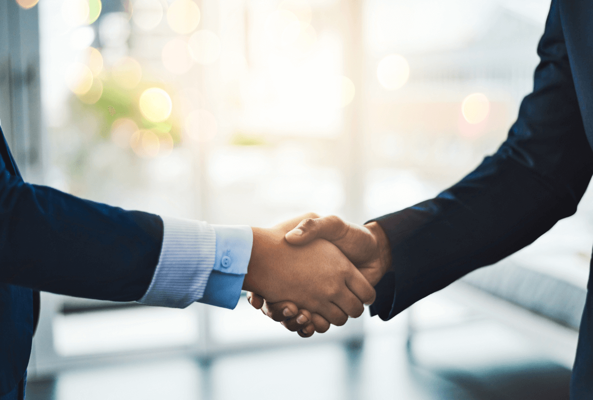 スーツを着た2人のビジネスパーソンが握手を交わしている様子